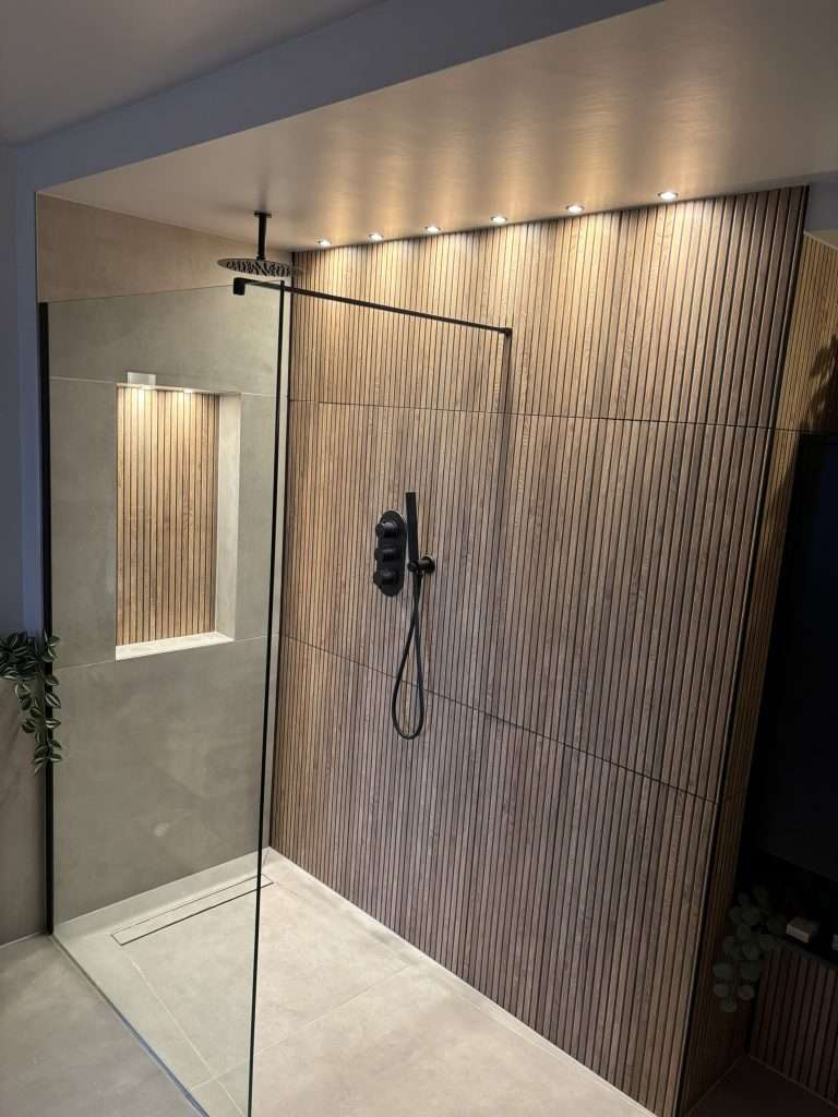 Walk-in shower renovation with black fittings, fluted wall tiles and illuminated recessed niche