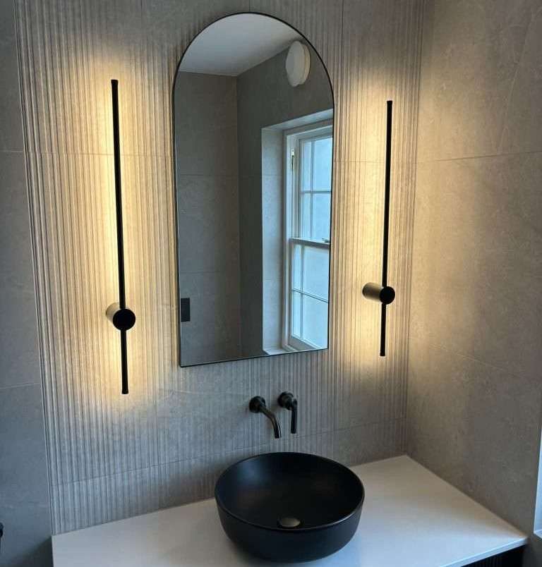 Modern bathroom renovation in Bristol with black basin, arched mirror and wall lighting